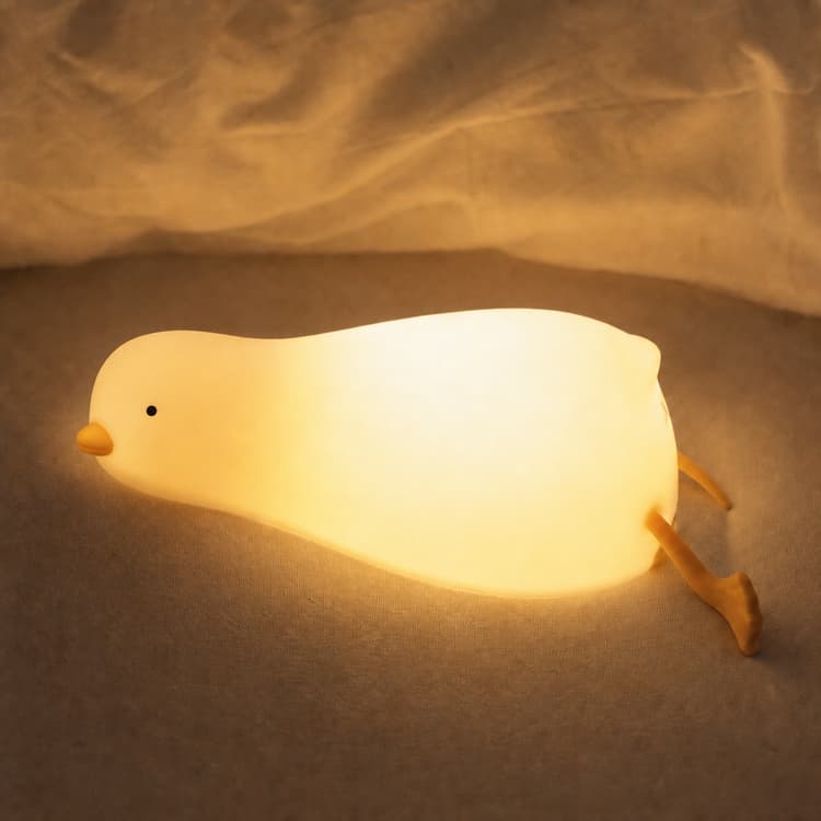 Glowing HAPPYBAG lying-flat duck night light on a soft brown surface