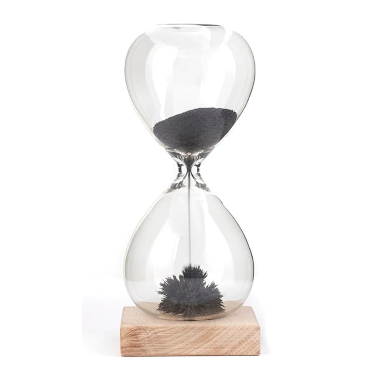 Glass magnetic hourglass with black iron powder on a wood base